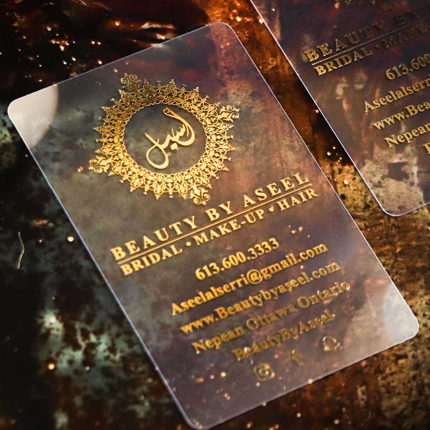 Transparent business card with gold text and design on a reflective surface
