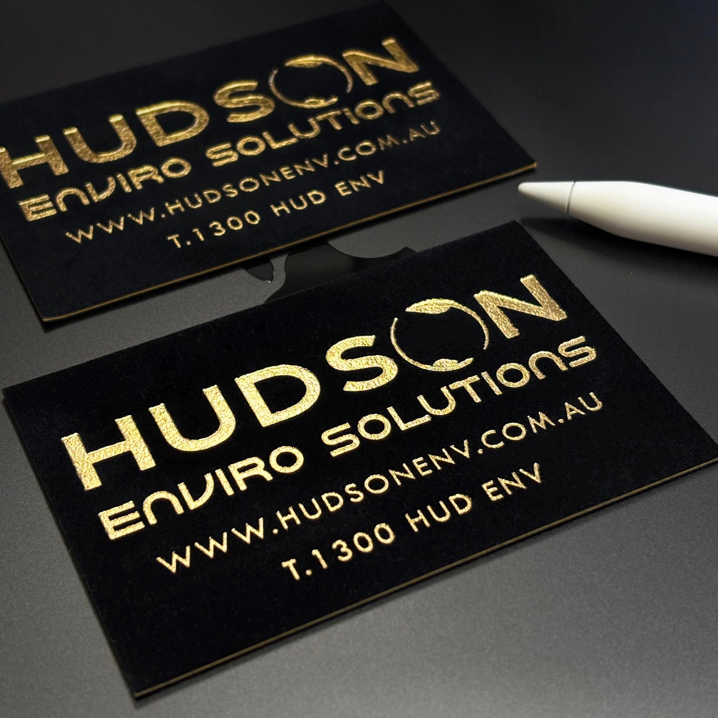 Premium black velvet business cards with embossed metallic gold foil logo stamping.