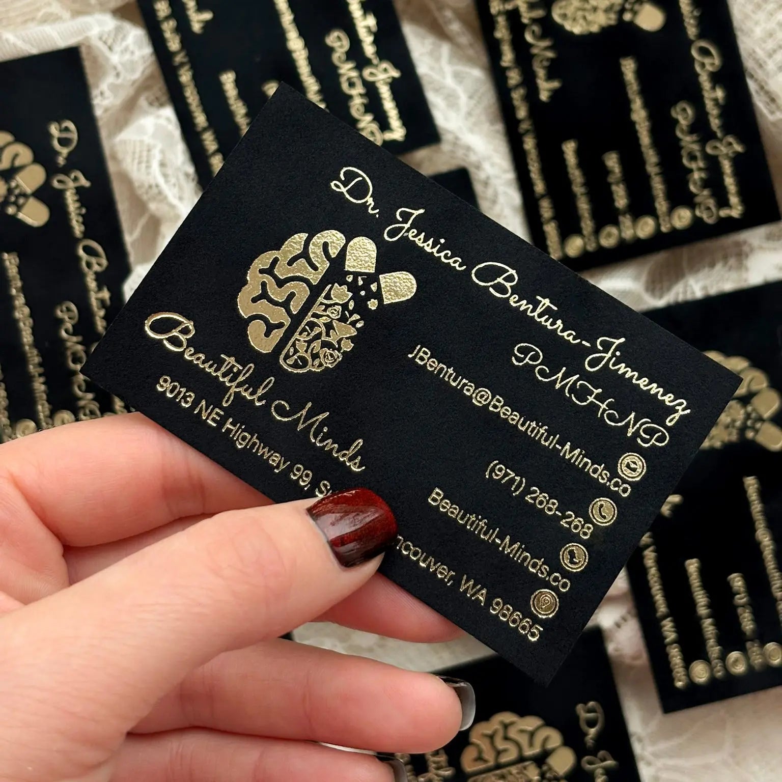 Holding a luxury custom business card with a velvety matte black finish and gold foil logo.