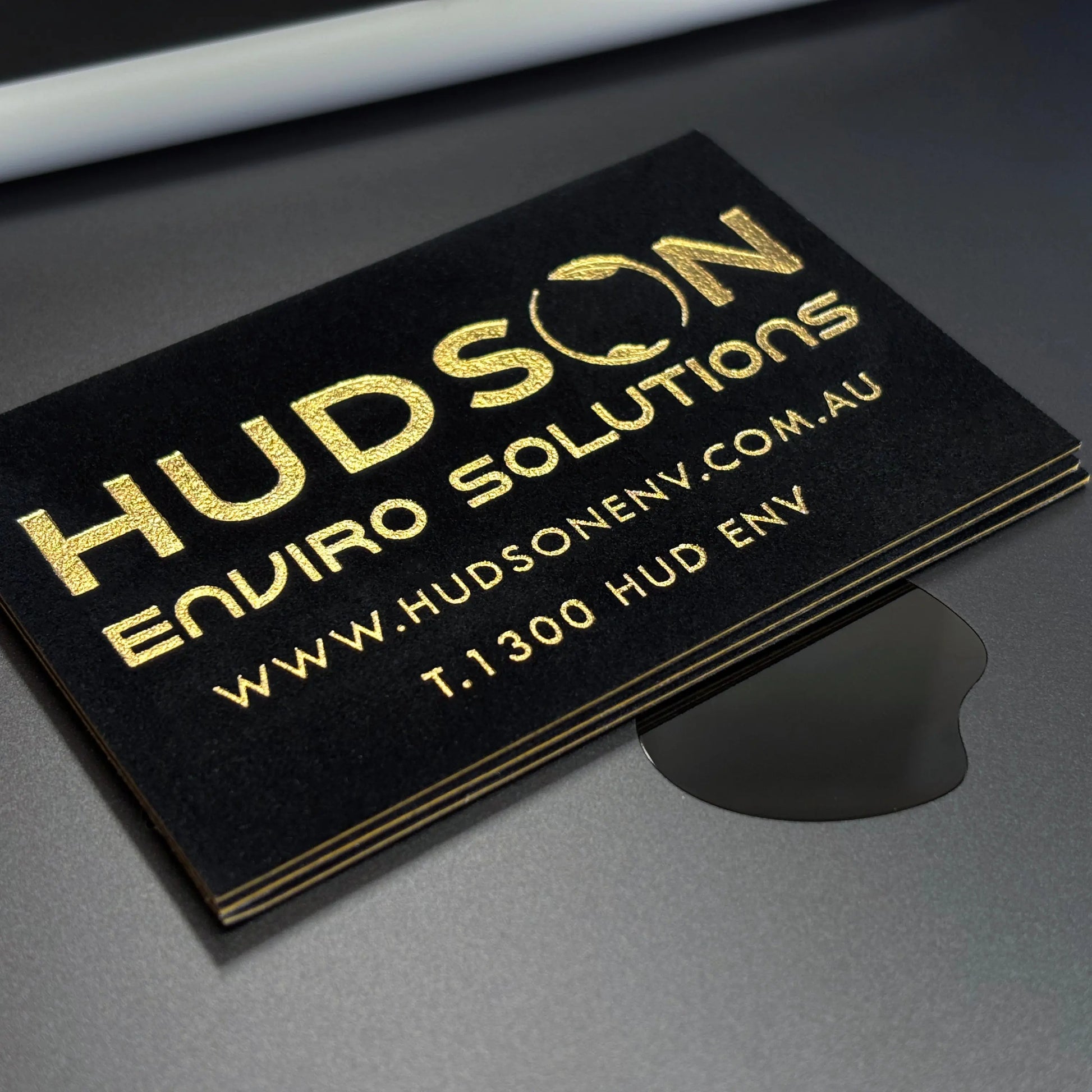 Close-up of custom metallic gold foil printing on luxury soft-touch black business card.