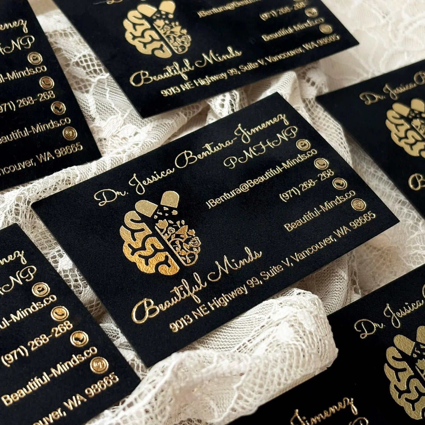 A stack of high-end black velvet business cards with precision gold foil edges and custom artwork