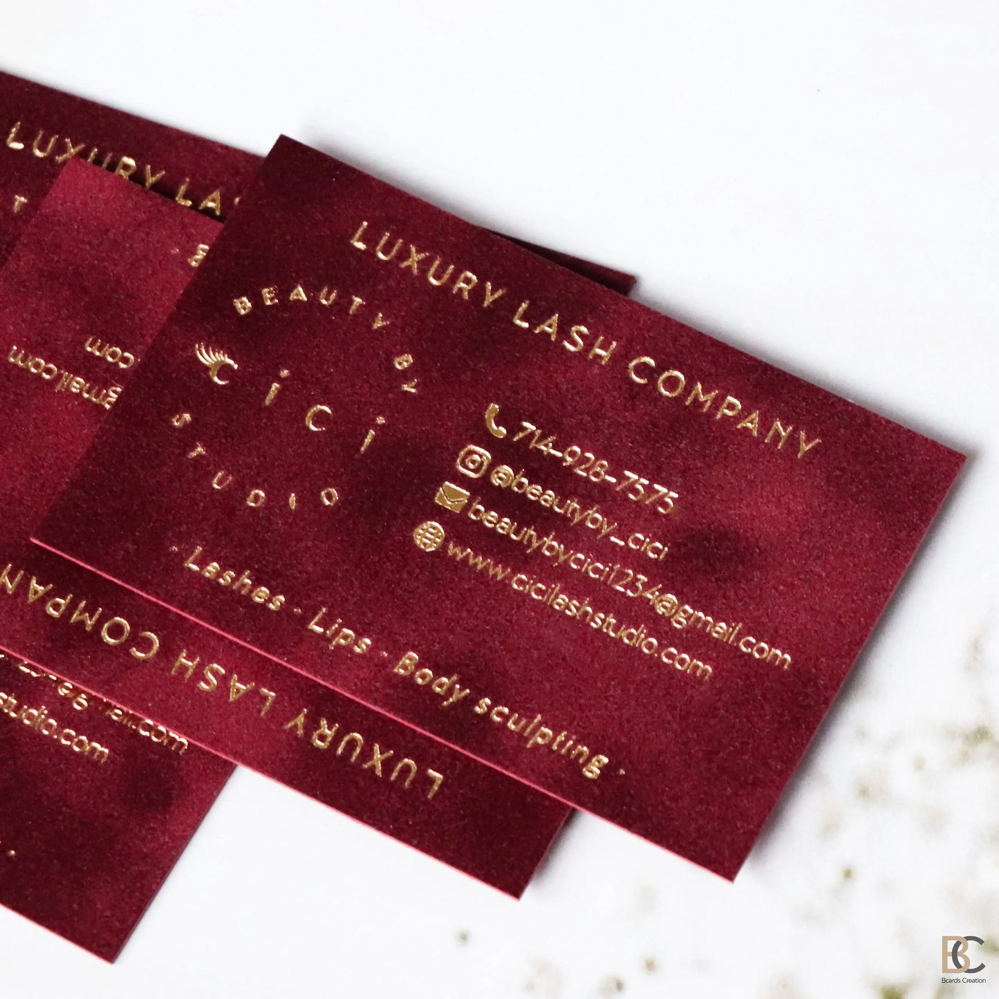 Close-up of gold foil stamping on red flocked velvet paper. Detailed view of the physical fabric texture and the reflective metallic gold finish on a premium business card.