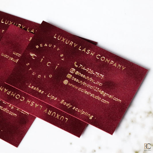 Close-up of gold foil stamping on red flocked velvet paper. Detailed view of the physical fabric texture and the reflective metallic gold finish on a premium business card.