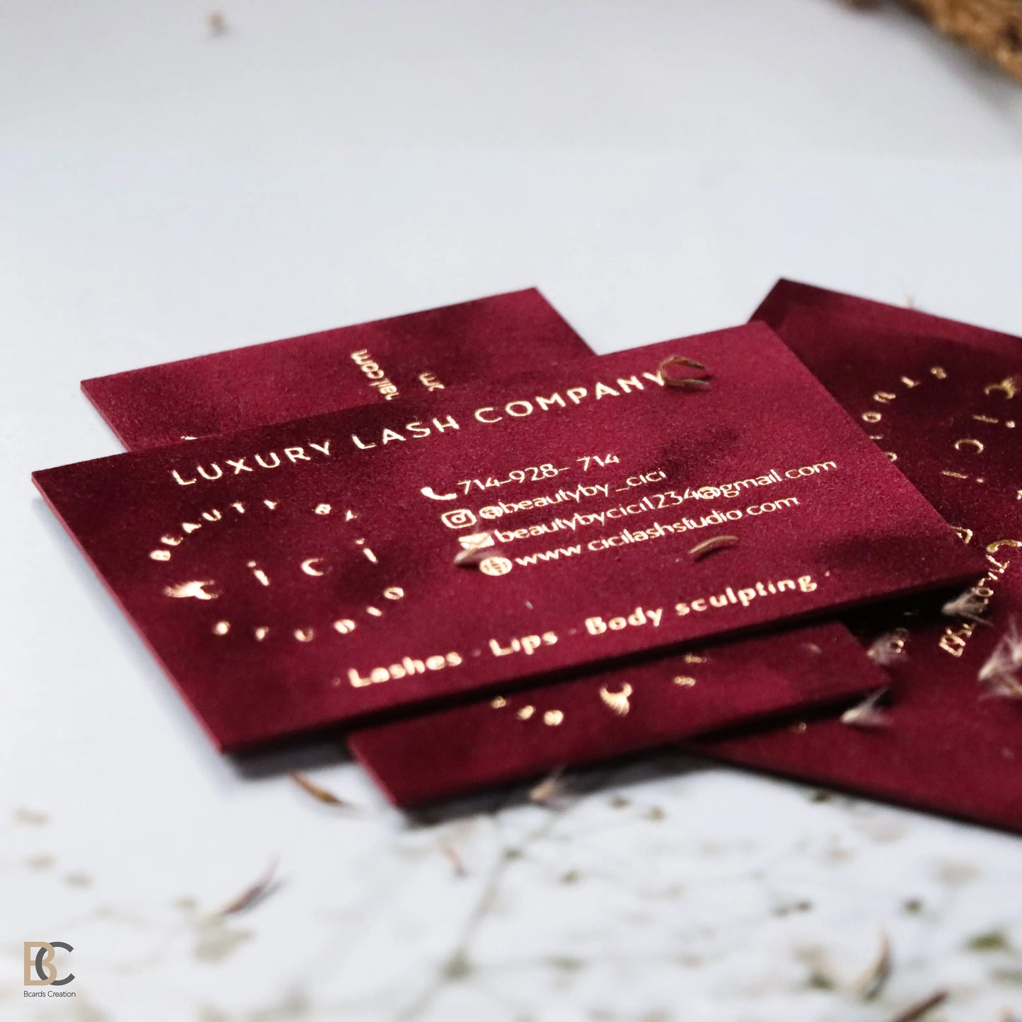 Close-up of gold foil stamping on red flocked velvet paper. Detailed view of the physical fabric texture and the reflective metallic gold finish on a premium business card.