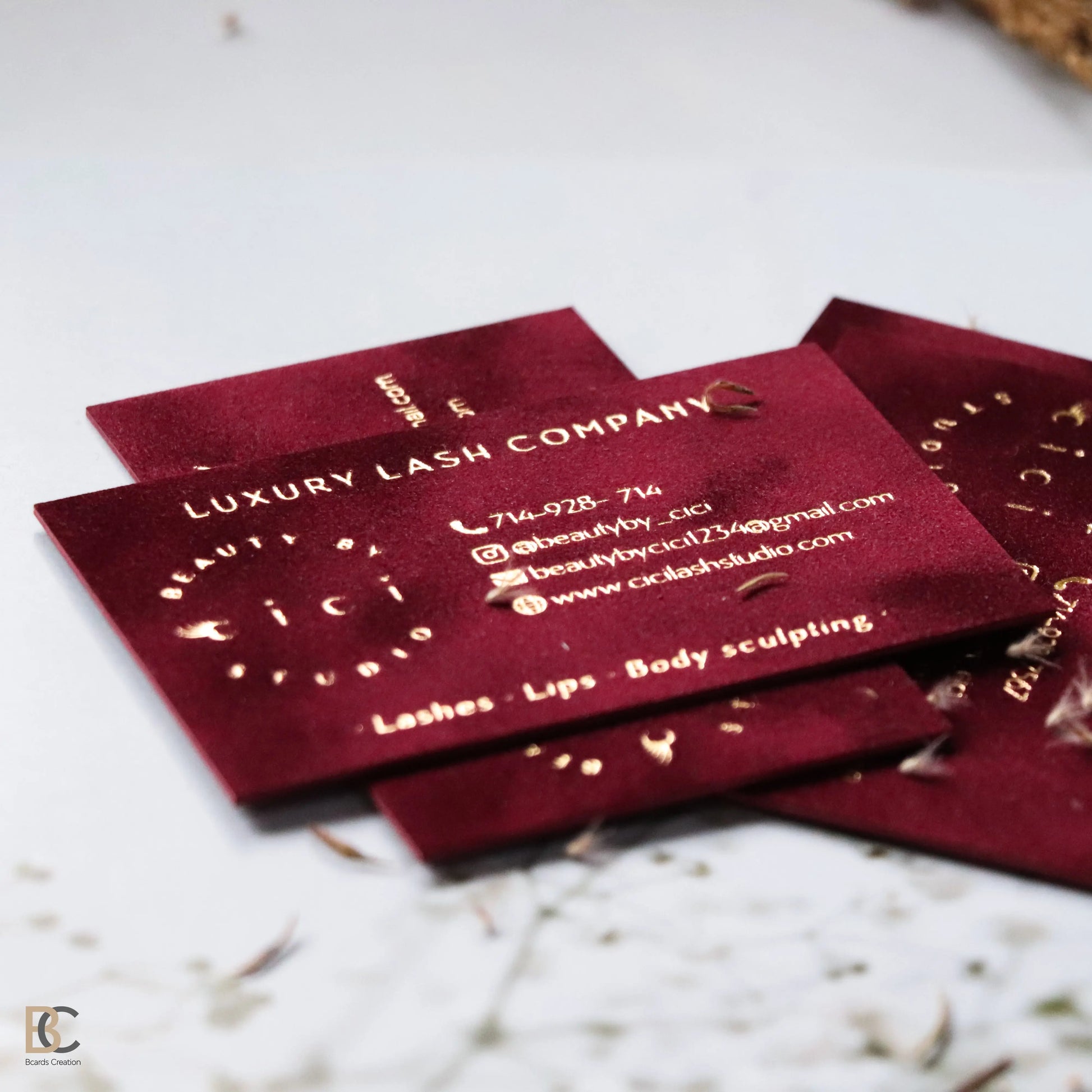 Close-up of gold foil stamping on red flocked velvet paper. Detailed view of the physical fabric texture and the reflective metallic gold finish on a premium business card.