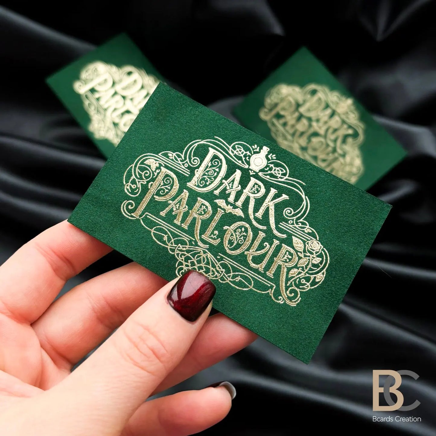 Hand holding a custom forest green velvet card with gold foil to showcase the professional 90x50 mm size and tactile finish
