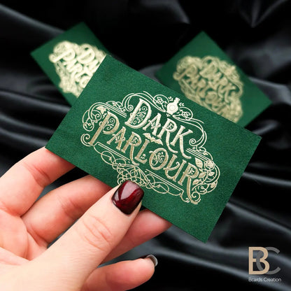 Hand holding a custom forest green velvet card with gold foil to showcase the professional 90x50 mm size and tactile finish